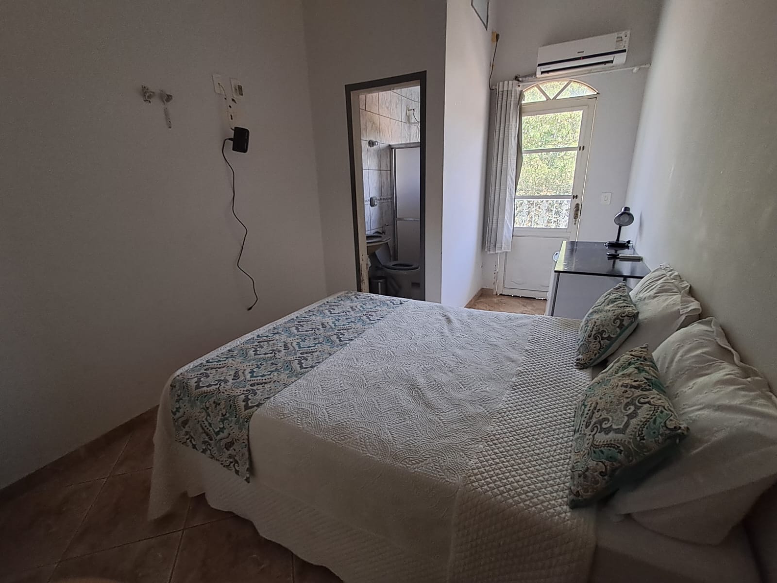 Cama de casal com almofadas estampadas e ar-condicionado